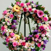 Large floral wreath with pink roses, daisies, and purple flowers