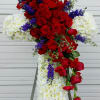 Standing floral cross with red roses, white chrysanthemums, and purple accents
