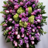 Large standing spray of pink roses, purple flowers, and green hydrangeas