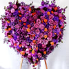 Large heart-shaped floral arrangement of purple, pink, and orange roses