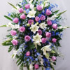 Large standing spray of pink roses, white lilies, and blue flowers