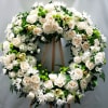 Large white floral wreath on a wooden stand