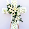 White floral cross with roses and daisies on a stand