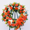 Heart-shaped wreath of orange roses and white daisies with an orange ribbon
