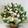 Arrangement of pale roses, white daisies, and purple flowers in a wooden basket