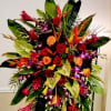 Large tropical floral arrangement with red and orange roses in a stand