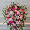 Large pink and red floral arrangement on an easel