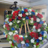 Large patriotic floral wreath on a wooden easel with red, white, and blue flowers