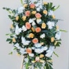 Standing floral spray with peach roses, white daisies, and yellow carnations