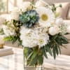 White floral bouquet with roses, gerbera daisies, hydrangea, and a succulent in a glass vase