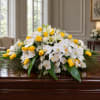 White orchids and yellow roses arranged on a casket