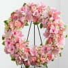 Pink floral wreath on a black stand