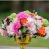 Pink and orange roses with pale hydrangeas in a gold vase