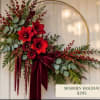 Holiday floral hoop arrangement with red blooms and a burgundy ribbon