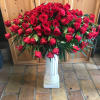 Large arrangement of red roses in a white pedestal vase