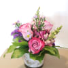 Pink roses and purple flowers arranged in a small vase