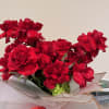 This stunning hand-tied bouquet features a generous arrangement of vibrant red roses