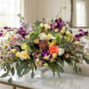 Mixed bouquet of roses, orchids, and lavender flowers in a glass vase