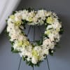 Heart-shaped floral wreath with white roses and chrysanthemums on a stand