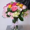 Bouquet of pink, yellow, and white roses in a glass vase with a ribbon