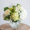 White and pale green floral arrangement in a glass vase