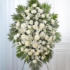 Large white funeral spray with mixed blooms and palm fronds
