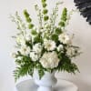 White floral arrangement in a white pedestal vase