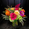 Bright mixed bouquet of roses and zinnias in a glass vase