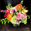 Colorful bouquet of roses, ranunculus, and orchids in a glass vase