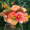 Mixed bouquet of peach, pink, and cream flowers in a clear glass vase