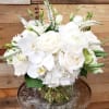White roses and orchids arranged in a clear glass vase