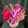 Pink roses and spotted orchids arranged in a white vase