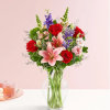 Bouquet of red roses and pink lilies in a clear glass vase