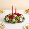 Red candles in a low floral centerpiece with white daisies and red roses