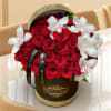 Red roses and white orchids arranged in a black hatbox