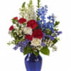 Red, white, and blue flowers arranged in a cobalt vase