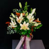 Bouquet of white lilies in a glass vase with a pink ribbon