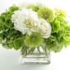 Green and white bouquet in a clear square vase