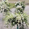 White floral funeral sprays with lilies and roses on stands