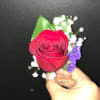 Single red rose with white baby's breath and purple filler held in hand