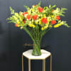 Mixed bouquet of red roses and yellow snapdragons in a glass vase