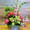 Mixed floral arrangement in a square glass vase with pink and green blooms