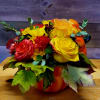 Bouquet of yellow and red roses with daisies in a pumpkin container