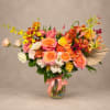 Colorful bouquet of roses, carnations, and orchids in a glass vase