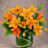 Orange lilies arranged in a round glass vase