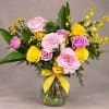 Pink and yellow roses in a glass vase with a yellow ribbon