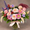 Mixed bouquet of pink and peach roses in a glass vase with a ribbon