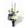 White floral arrangement in a blue glass vase with tall stems
