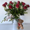 This arrangement features 12 long stems of red roses with a branch