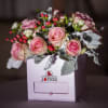 Pink roses arranged in a white box with red berry accents